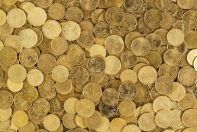 A close-up shot of Euro coins scattered in a pile, showcasing a rich golden texture.
