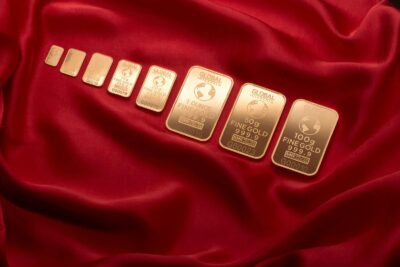 Array of fine gold bars displayed on rich red fabric, symbolizing wealth and luxury.